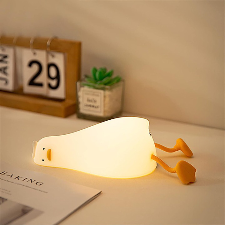 La veilleuse canard Ducky en position allongée sur un bureau afin d'illuminer la pièce.