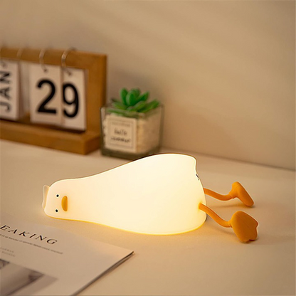 La veilleuse canard Ducky en position allongée sur un bureau afin d'illuminer la pièce.